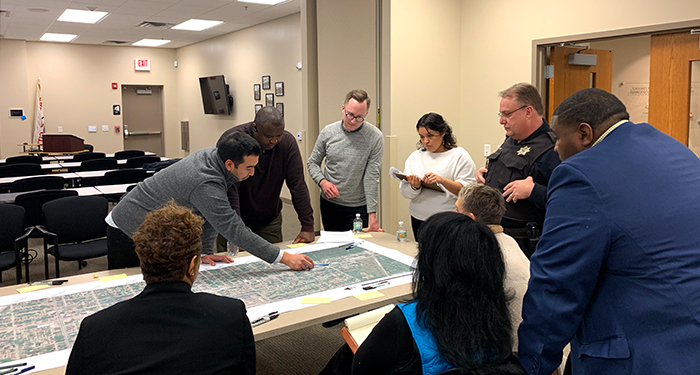 Group of people pointing out items on a map and discussing around a table
