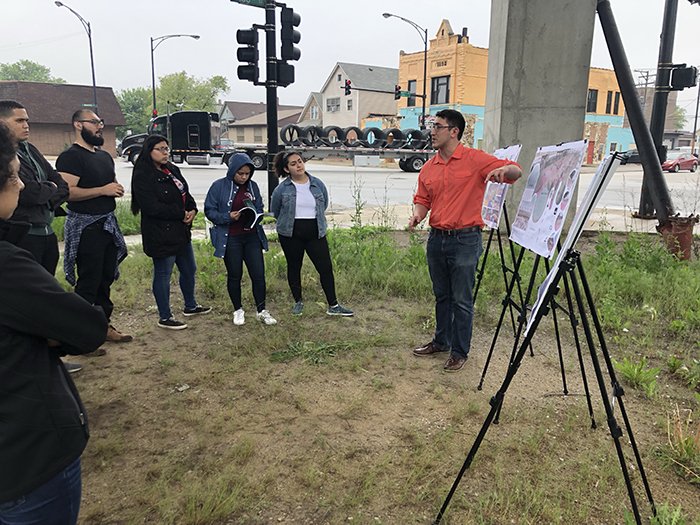 A speaker showing a map to a group of people standing on site.