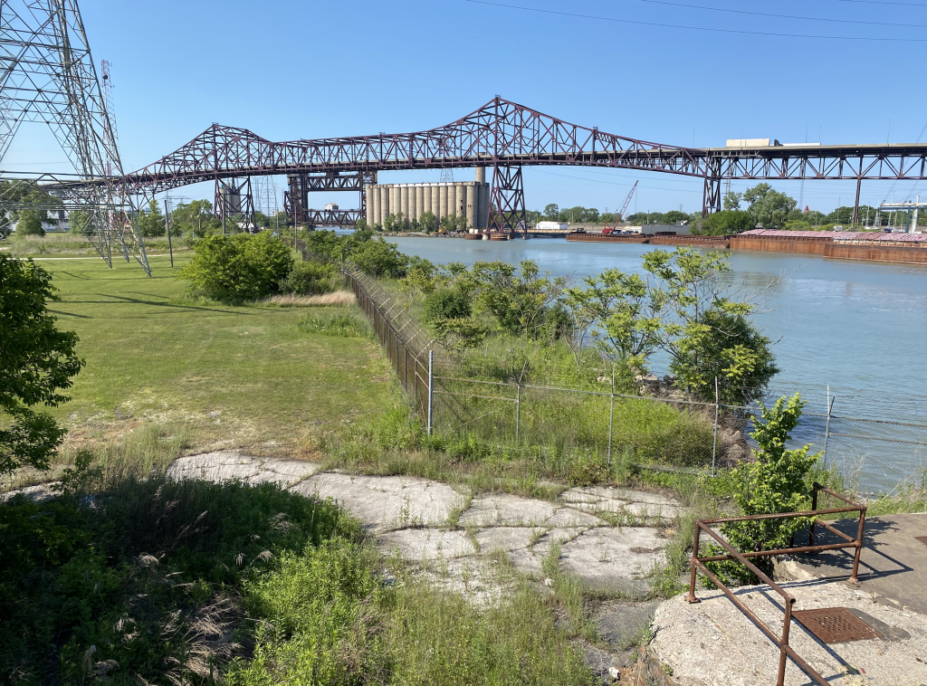 Green fenced area next to the Calumet River with a bridge in the background