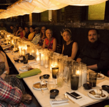 Chicago Community Trust’s “On the Table” event photo, where people are gathered around the food table talking about local issues and coming together. 