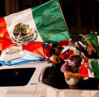 Car driving with people holding a large Mexican flag, photo by Tess Crowley of Chicago Tribune 
