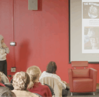 Speaker presents at UIC event with audience seated, slides projected on screen, and Great Cities Institute branding visible. 