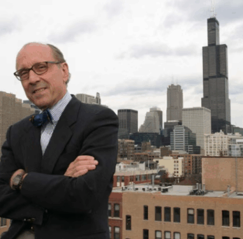 Portrait of Dr. David C. Perry standing with arms crossed on a rooftop, with the Chicago skyline and Willis Tower behind him. 