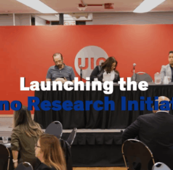 Panel discussion at UIC event launching Latino Research Initiative, with speakers seated on stage and audience in attendance. 