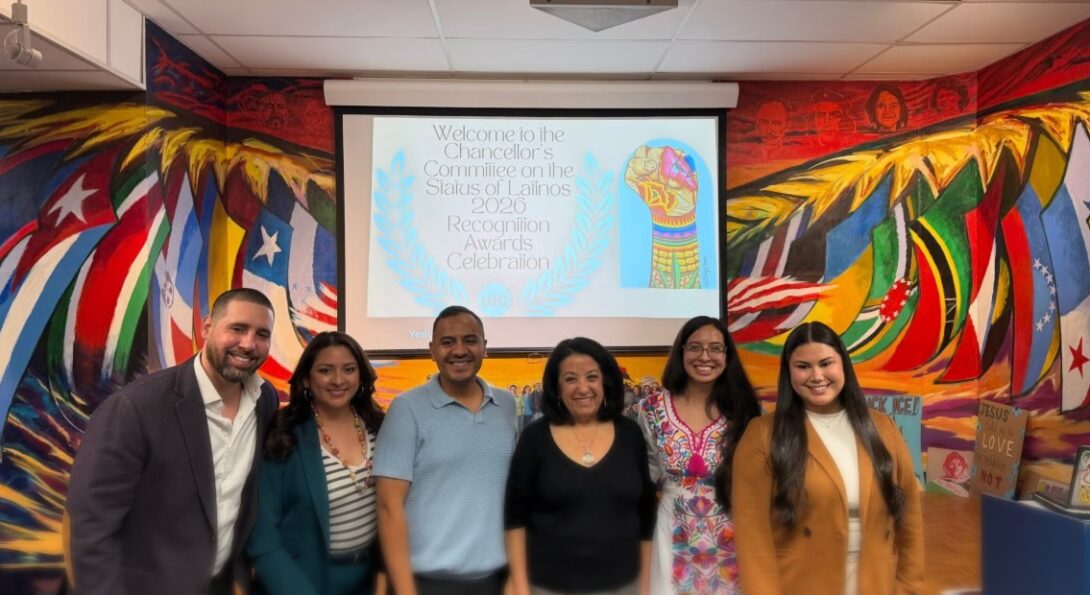 Group photo of UIC faculty, staff, and community leaders standing together in front of a colorful mural during a Latine community recognition event.