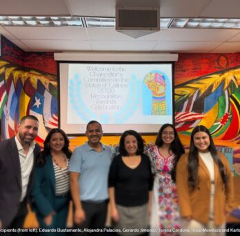 Group photo of UIC faculty, staff, and community leaders standing together in front of a colorful mural during a Latine community recognition event. 