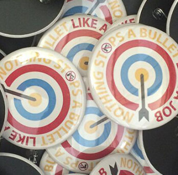 Close-up of buttons with target graphics and text reading “Nothing stops a bullet like a job.” 