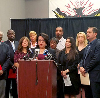 Group of speakers standing behind a podium at a press conference about youth employment and economic opportunity. 