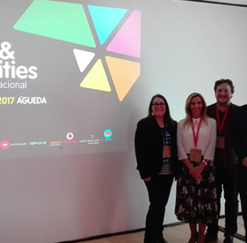 Three presenters standing beside a projected “Energy & Smart Cities” conference slide at an event in Águeda, Portugal. 