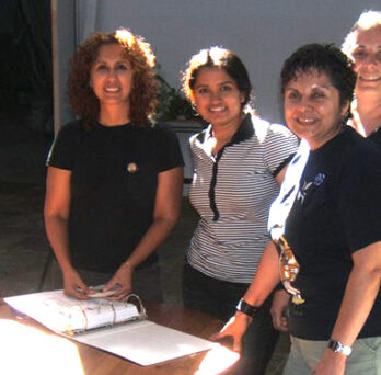 Group of five women standing together around a table during a workshop or meeting. 