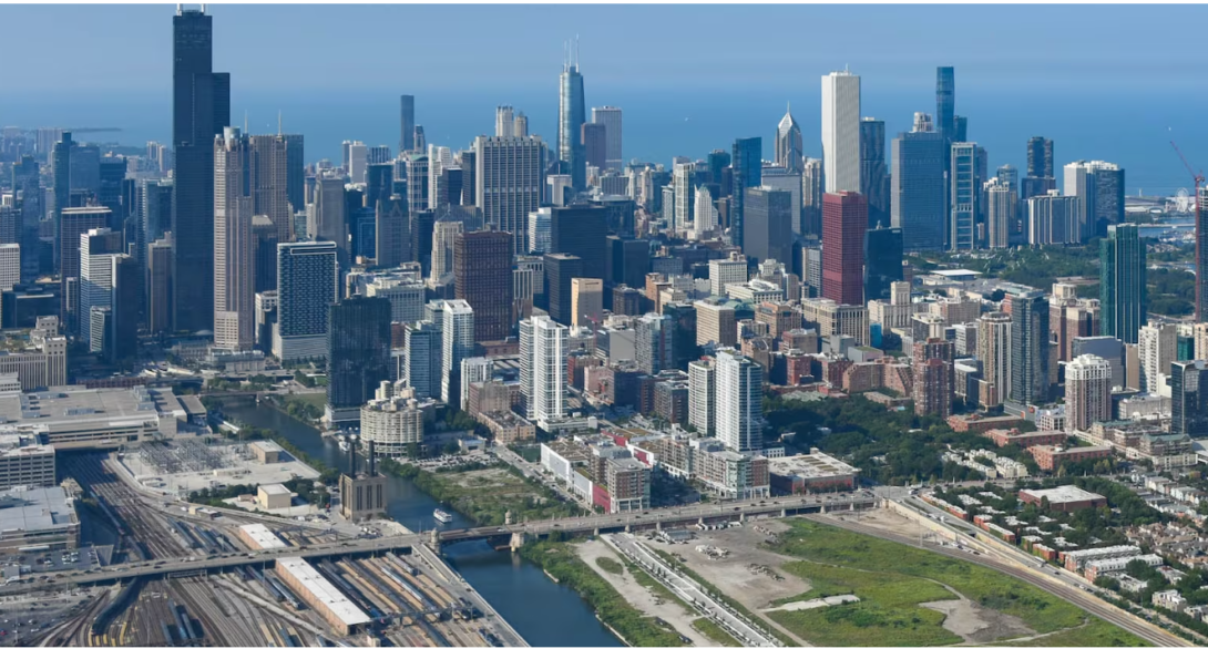 Aerial view of downtown Chicago, showing the skyline, high-rise buildings, highways, rail lines, and surrounding neighborhoods near Lake Michigan. (Curtis Waltz / aerialscapes.com)