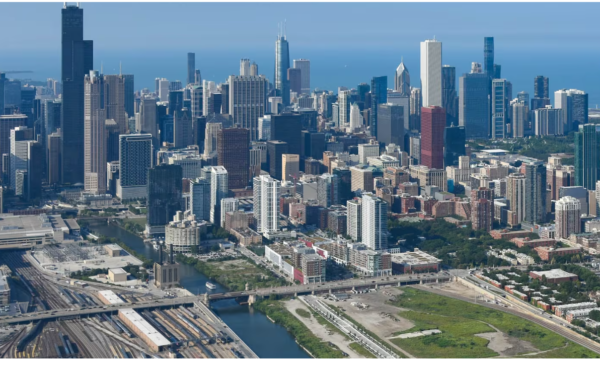Aerial view of downtown Chicago, showing the skyline, high-rise buildings, highways, rail lines, and surrounding neighborhoods near Lake Michigan. (Curtis Waltz / aerialscapes.com)